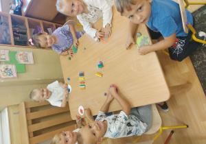 Dzieci siedzą przy stole i lepią z plasteliny